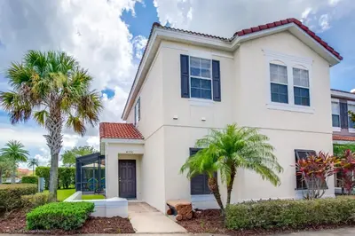 a white house with palm trees at Ev4550 - Bella Vista Haven in Kissimmee