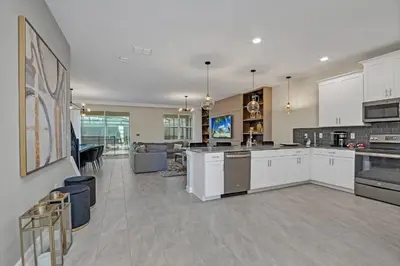 a kitchen with white cabinets and a living room at Ev4568 - Storey Oasis in Kissimmee