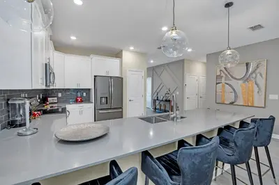 a kitchen with a large counter with blue chairs at Ev4568 - Storey Oasis in Kissimmee