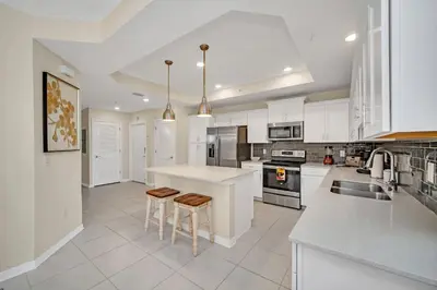 a kitchen with white cabinets and a kitchen island with stools at Ev208 - The Storey Condo in Kissimmee