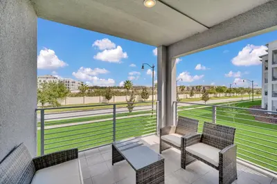 a balcony with two chairs and a view of a field at Ev208 - The Storey Condo in Kissimmee