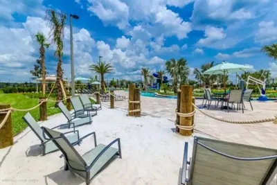 a patio with chairs and tables and a pool at Ev4755 - Tranquil Haven Villa in Kissimmee