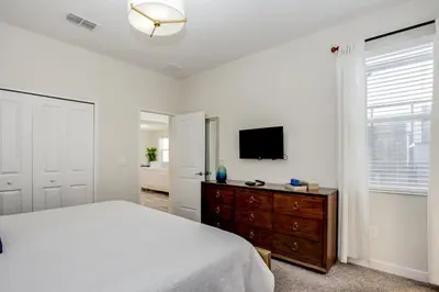 a white bedroom with a bed and a tv at Ev4778 - Paradise Cove Villa in Kissimmee