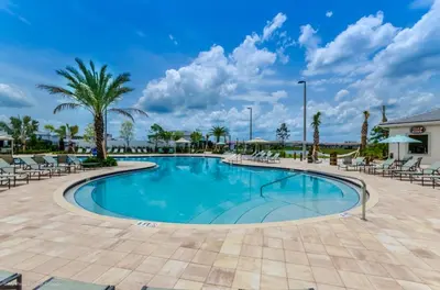 a swimming pool at a resort with chairs and palm trees at Ev4815 - Regal Escape Villa in Kissimmee