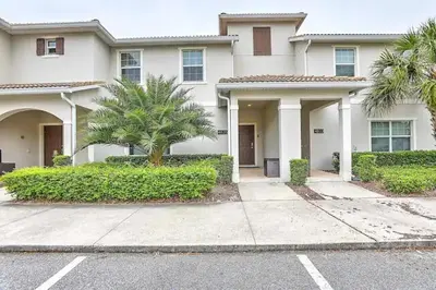 a white house with a palm tree in front of it at Ev4835 - Adventure Cove Villa in Kissimmee