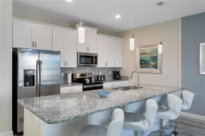 a kitchen with a granite counter top and white cabinets at Ev4887 - Golden Palms Retreat in Kissimmee