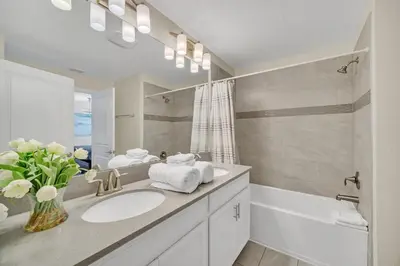 a bathroom with a sink and a tub and a mirror at Ev4987 - Raceway Retreat in Kissimmee