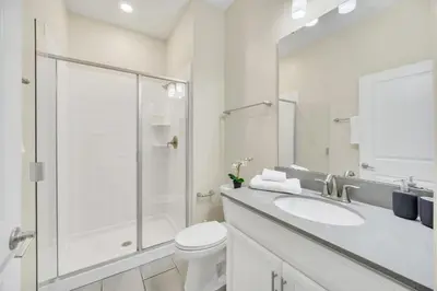 a white bathroom with a toilet and a glass shower at Ev4987 - Raceway Retreat in Kissimmee