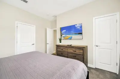 a white bedroom with a bed and two white doors at Ev4987 - Raceway Retreat in Kissimmee
