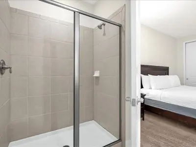 a bathroom with a glass shower and a bed at Ev7501 - Encore in Orlando