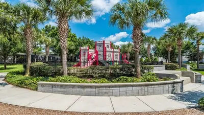 a red house with palm trees in front of a playground at 7664Unit403 in Orlando