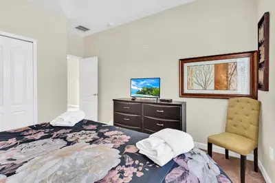 a bedroom with a bed and a chair and a television at Ev8927 - Paradise Dream Retreat in Kissimmee