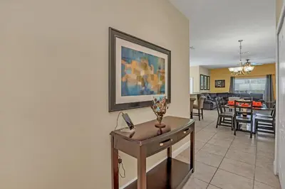 a living room with a table and a painting on the wall at Ev8950 - Paradise Oasis Villa in Kissimmee