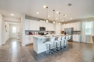 a kitchen with white cabinets and a large island with bar stools at Ev9071- Solara Cove in Orlando