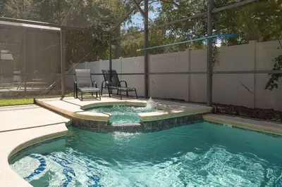 a swimming pool with two chairs and a fountain at Casa 4Q c/ Piscina & Spa no Veranda Palms in Kissimmee