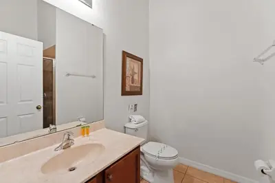 a bathroom with a sink and a toilet and a mirror at Casa 4Q c/ Piscina & Spa no Veranda Palms in Kissimmee