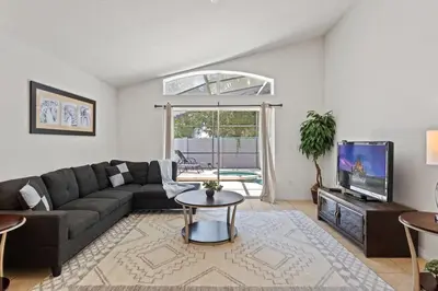 a living room with a couch and a tv at Casa 4Q c/ Piscina & Spa no Veranda Palms in Kissimmee