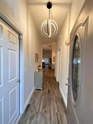 a hallway of a home with a door and wooden floors at Beautiful 5BR home near Disney with private pool, large yard & BBQ in Orlando