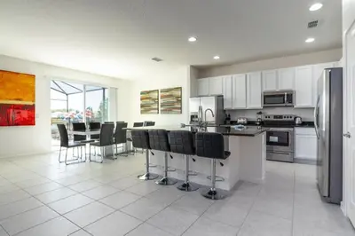 a kitchen with white cabinets and black bar stools at BellaVida 8 bed Theme Rooms in Kissimmee