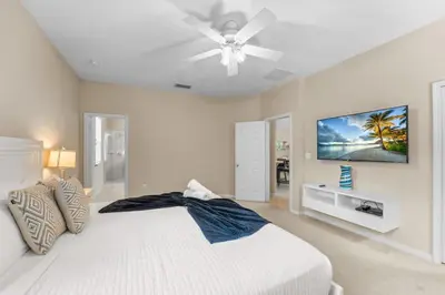 a bedroom with a white bed and a ceiling fan at 4 Bed Close to Disney Private Pool in Kissimmee