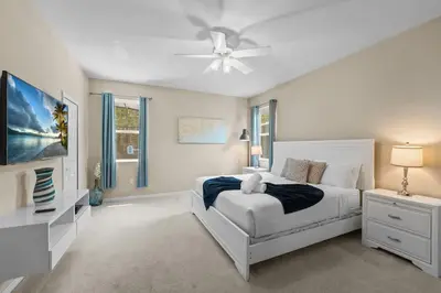 a white bedroom with a bed and a ceiling fan at 4 Bed Close to Disney Private Pool in Kissimmee