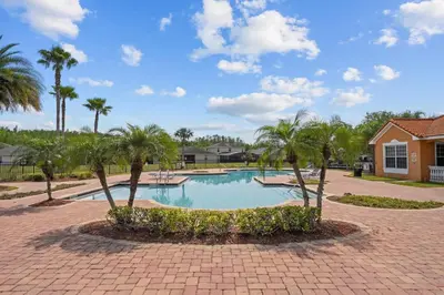 a swimming pool with palm trees and a house at 4 Bed Close to Disney Private Pool in Kissimmee