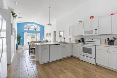 a kitchen with white cabinets and a table in it at Casa Térrea 4Q c/ Piscina e Game Room in Kissimmee