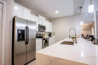 a kitchen with white cabinets and a stainless steel refrigerator at 8952 Private pool 4bd townhome in Kissimmee