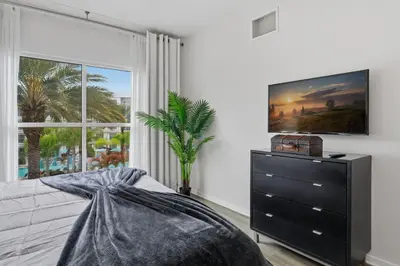 a bedroom with a dresser and a large window at Orlando Getaway with Pool View Balcony in Orlando