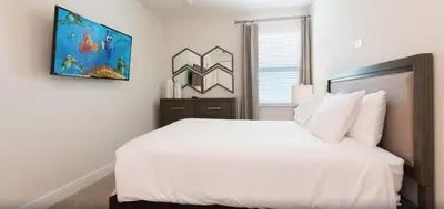 a bedroom with a white bed and a painting on the wall at Ultimate Mansion-9Bed-PoolSpaGame in Orlando