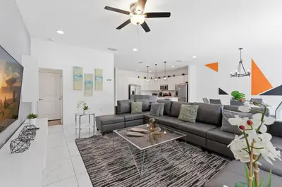 a living room with a couch and a ceiling fan at Chic Modern Escape 12BR Pool and Game Room in Kissimmee