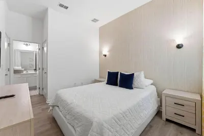 a white bedroom with a bed and a bathroom at Chic Modern Escape 12BR Pool and Game Room in Kissimmee