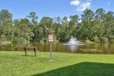 a park bench in front of a pond with a fountain at 
