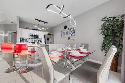 a dining room with a glass table and red chairs at 3179 Yellow Lantana Lane in Kissimmee