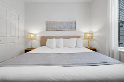 a white bedroom with a large bed with two lamps at Luxury 2BR Epic Universe Condo at Vista Cay 3029 by Vista Cay Resort in Orlando