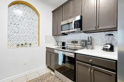 a kitchen with gray cabinets and a stove and microwave at Luxury 2BR Epic Universe Condo at Vista Cay 3029 by Vista Cay Resort in Orlando