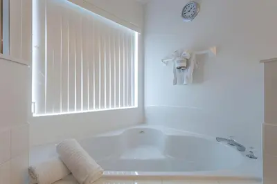 a white bathroom with a tub and a window at Private Pool with spa and Game Room Near Disney in Kissimmee