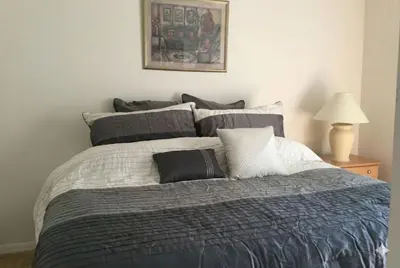 a bed with gray and white sheets and pillows at Private Pool with spa and Game Room Near Disney in Kissimmee