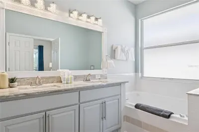 a bathroom with a sink and a large mirror at Disney World, Universal Epic Waterfront Modern Home - Private Pool And Game Room in Kissimmee