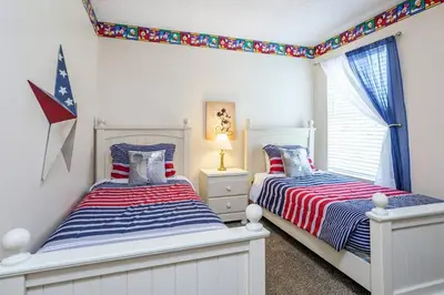 two beds in a bedroom with a flag on the wall at Luxury 7BR w Pool Lake View at Berkley in Kissimmee