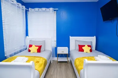 two beds in a blue room with red and yellow pillows at 3BR Disney Home with Pool , Arcade and Hot Tub in Kissimmee