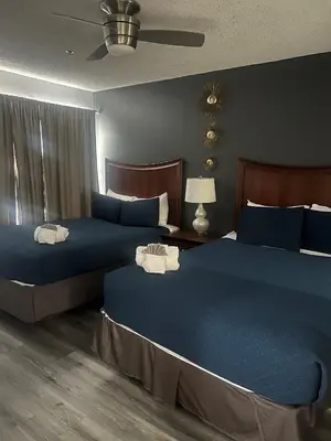 two beds in a hotel room with blue sheets at Condo Epic Universal Disney Free Parking in Orlando
