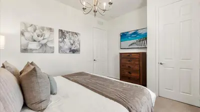 a white bedroom with a bed and a chandelier at Upstay Great 3BR Condo w Scenic Views & Patio in Orlando