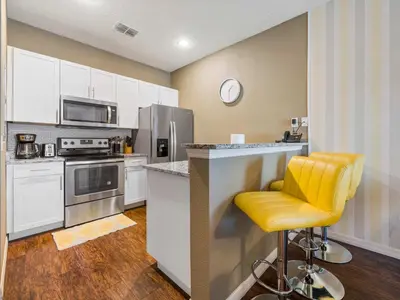a kitchen with white cabinets and a yellow bar stool at Elegant Townhome at West Lucaya in Kissimmee