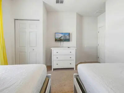 a white bedroom with two beds and a dresser at Elegant Townhome at West Lucaya in Kissimmee