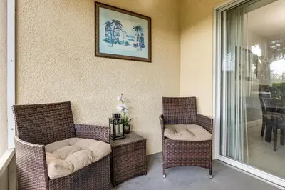 two chairs and a couch on a porch with a table at 5 Mi to WDW! Spacious Resort Escape with Pool Access in Kissimmee
