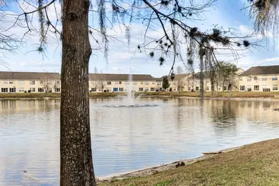a lake in front of a building with a fountain at 5 Mi to WDW! Spacious Resort Escape with Pool Access in Kissimmee