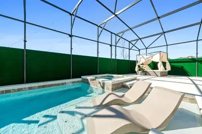 a swimming pool with two lounge chairs and a glass roof at Resort-Style Living w Private Pool & Amenities in Kissimmee