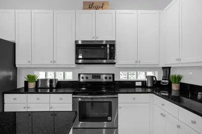 a kitchen with white cabinets and a stove and a microwave at 9 BR Family Home 8 Min to Disney SON104 in Kissimmee