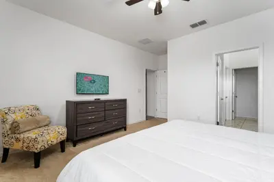 a bedroom with a bed and a chair and a dresser at 9 BR Family Home 8 Min to Disney SON104 in Kissimmee